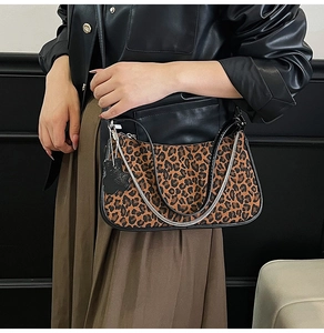 Detail of leopard print underarm bag with silver chain and black bear charm accessory
