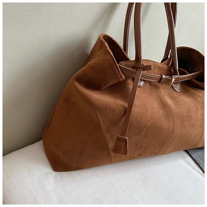 Close-up of brown suede tote bag showing detailed texture and smooth leather handle