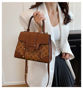 Brown monogram handbag shown with white blazer and black pleated skirt on a model