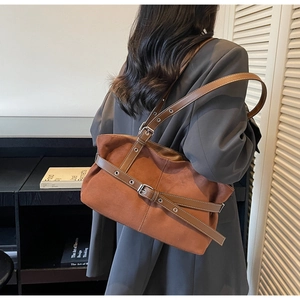 Detail of adjustable strap with metal buckles on a vintage brown suede shoulder bag