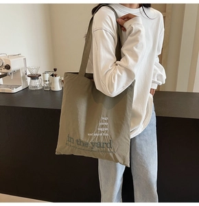 Detail of army green canvas tote bag with botanical lettering in a cafe setting