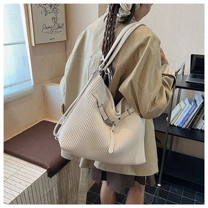 Detail of pleated beige tote bag showing textured fabric and silver side buckle