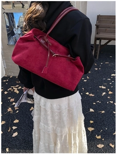Detailed texture of burgundy suede tote bag featuring metallic buckle and thin shoulder strap