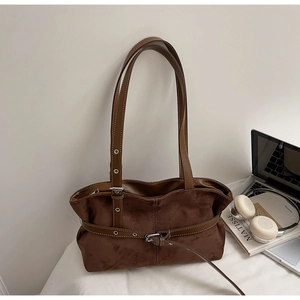Detailed close-up of brown suede tote bag featuring white stitching and silver buckles