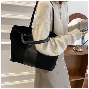 Detail of a large black canvas tote bag with leather straps and vertical trim for commute