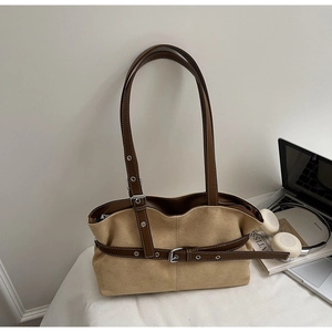 Detail of khaki suede tote bag with brown leather trim and metal buckle on office desk