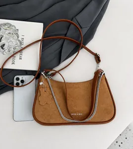 Detail of a brown suede crescent bag with silver chain and adjustable shoulder strap