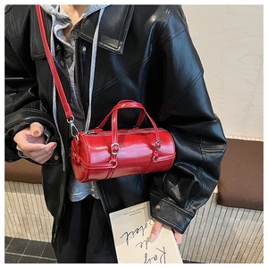 Glossy red cylinder bag shown as a crossbody detail against a black leather jacket