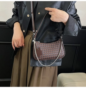 Detailed view of brown woven leather crescent shoulder bag with chain strap and pendant