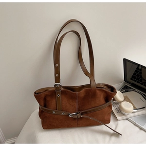 Close-up of vintage brown suede tote bag with metal buckle on a desk with books