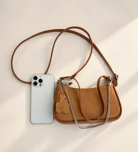 Brown mini hobo bag size comparison with a smartphone showing suede and leather details