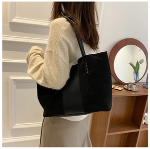 Detail of black tote bag showing smooth PU leather and suede texture with woven accents
