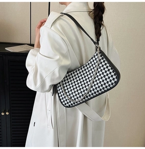 Detail of checkered hobo bag with black leather strap and silver chain accessory