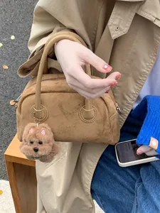 Vintage Handtasche aus braunem Wildlederimitat mit Plüschhund-Anhänger auf Holzbank