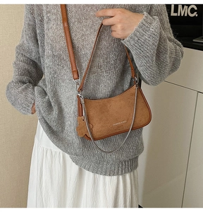 Detail view of brown faux suede shoulder bag with gold chain and floral charm decoration