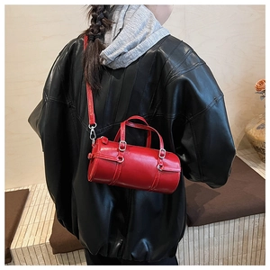 Detail of red cylinder handbag on black leather coat with adjustable shoulder strap