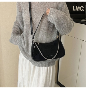 Detail of black leather crescent underarm bag with silver chain on model outfit
