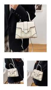 Detail of cream leather handbag featuring floral print flap and gold metal studs