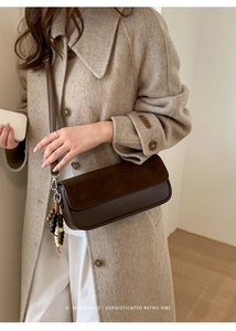 Detail of retro leather crossbody bag with wooden bead charm on a model in a tweed coat