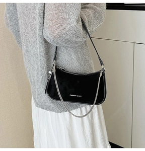 Detail of black suede underarm bag with silver chain and white fashion text logo