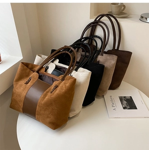 Multiple colors of large suede tote bags displayed in a minimalist indoor setting