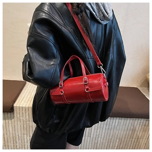 Detail of red glossy barrel bag featuring silver hardware and adjustable shoulder strap