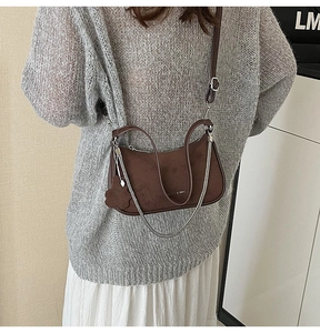 Close-up of vintage dark brown suede shoulder bag with elegant chain detail and charm