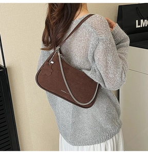 Detail view of dark brown faux suede underarm bag with silver chain and floral charm