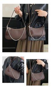 Macro shot of large square woven leather texture and metal chain detail on brown crescent bag