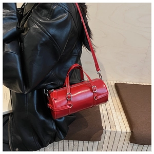 Detail of red cylinder PU bag with silver hardware on a shoulder-worn model