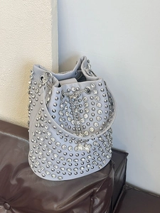 Litschimuster Beuteltasche mit Nieten und Perlen auf einer braunen Lederbank