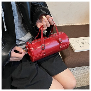 Detail of red cylinder bucket bag with glossy finish and silver buckles on black outfit