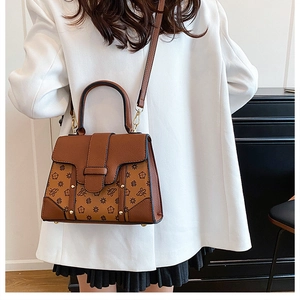 Brown monogram crossbody bag worn over the shoulder with a white casual suit