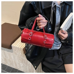 Detail of red cylindrical handbag with glossy leather finish and silver zippers