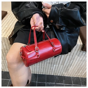 Detail of red cylindrical handbag with silver hardware and smooth PU leather texture
