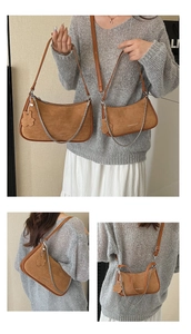 Detail view of two brown suede underarm bags with metal chain and floral pendant