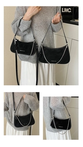 Detail of black suede underarm bag featuring silver chain decor and adjustable straps