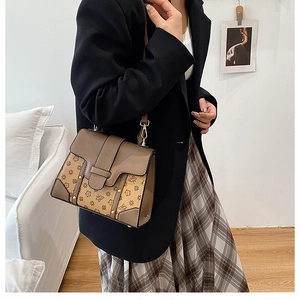 Detail of vintage floral bee print handbag featuring brown leather stitching and gold buckle