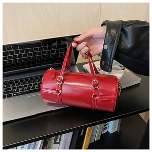 Detail of red cylindrical handbag in glossy leather with silver hardware and top handles