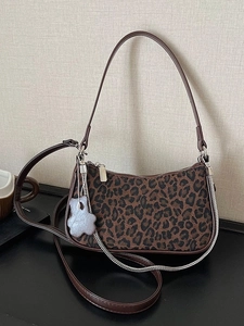 Vintage leopard print underarm bag with crescent shape, brown leather straps, and bear charm