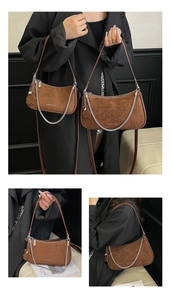 Detail of brown suede underarm bag featuring silver chain and floral bag charm