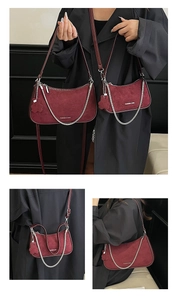 Detail view of burgundy suede crescent bags with silver chains and floral charm