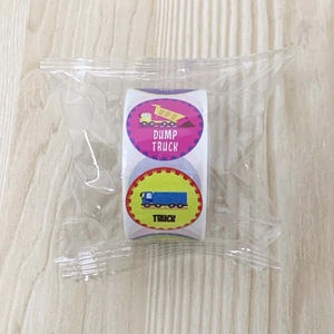 Macro detail of cartoon dump truck reward stickers on a roll in plastic packaging