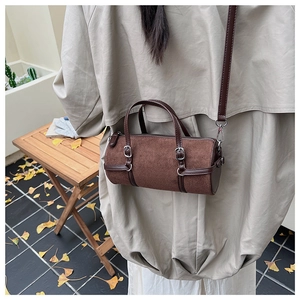 Detail of dark brown cylindrical crossbody bag in suede and leather with silver buckles