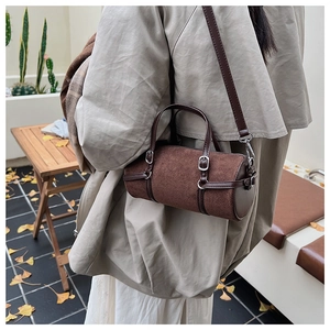 Retro brown cylinder handbag with leather straps worn with a stylish trench coat