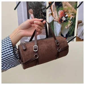Detail of dark brown cylindrical suede bag with leather straps and silver buckles