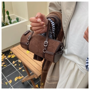 Detail view of vintage dark brown cylinder bag with suede texture and silver hardware