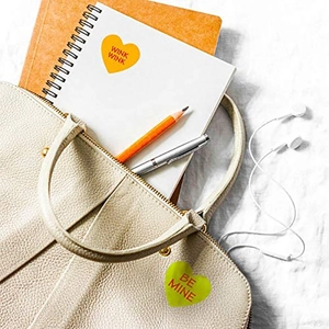 Heart-shaped Valentine's Day stickers with 'Wink Wink' text on notebook and bag