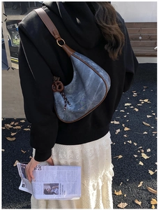 Détail du sac à bandoulière en croissant avec garniture en cuir brun et pendentif spiralé