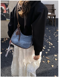 Détail du sac hobo en denim bleu avec garniture en cuir marron et anneau en métal doré